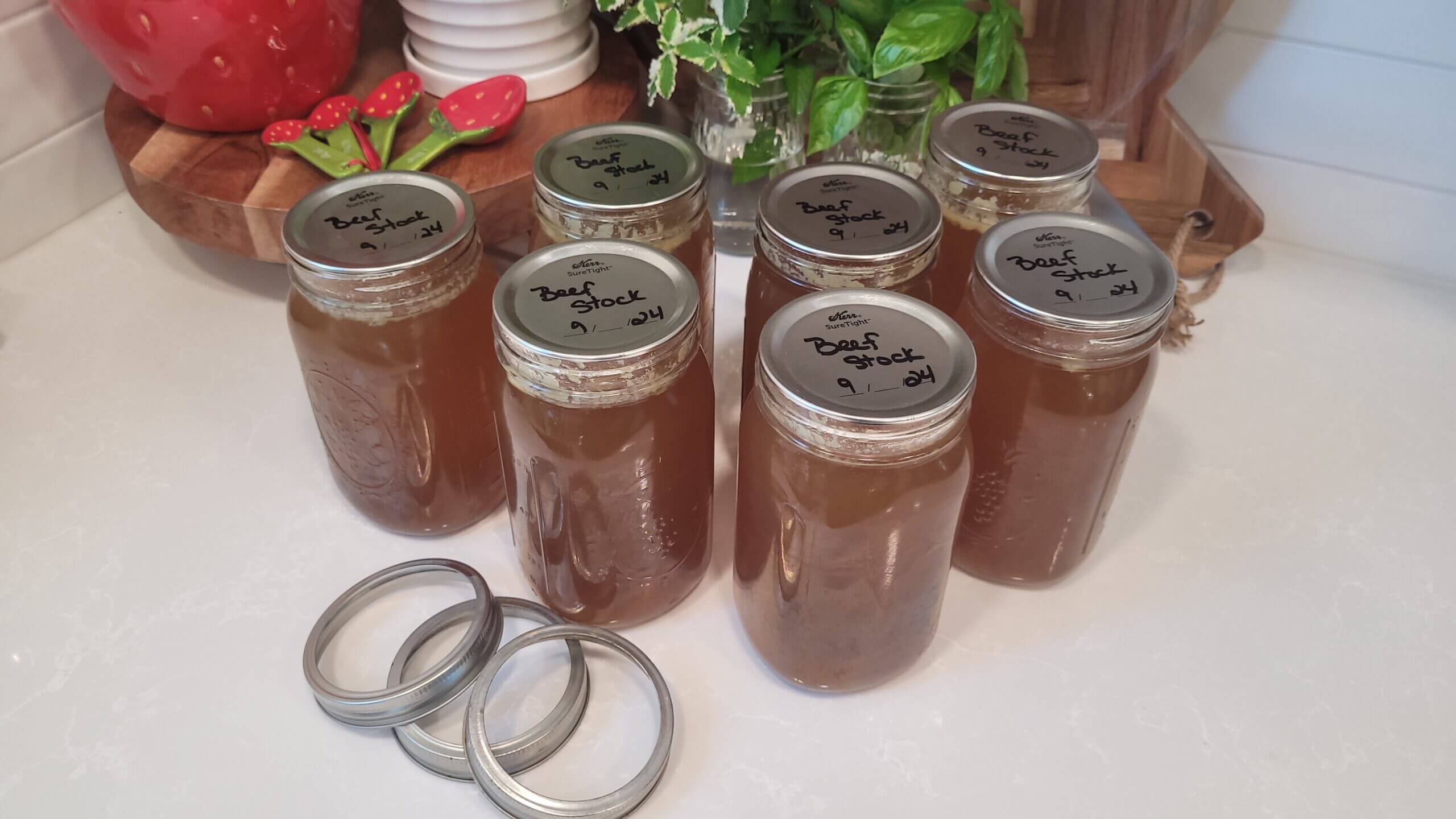canning jars filled with beef stock sittiing on a counter