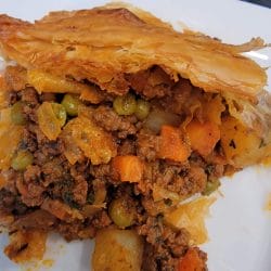 A slice of beef pot pie fully cooked on a white plate