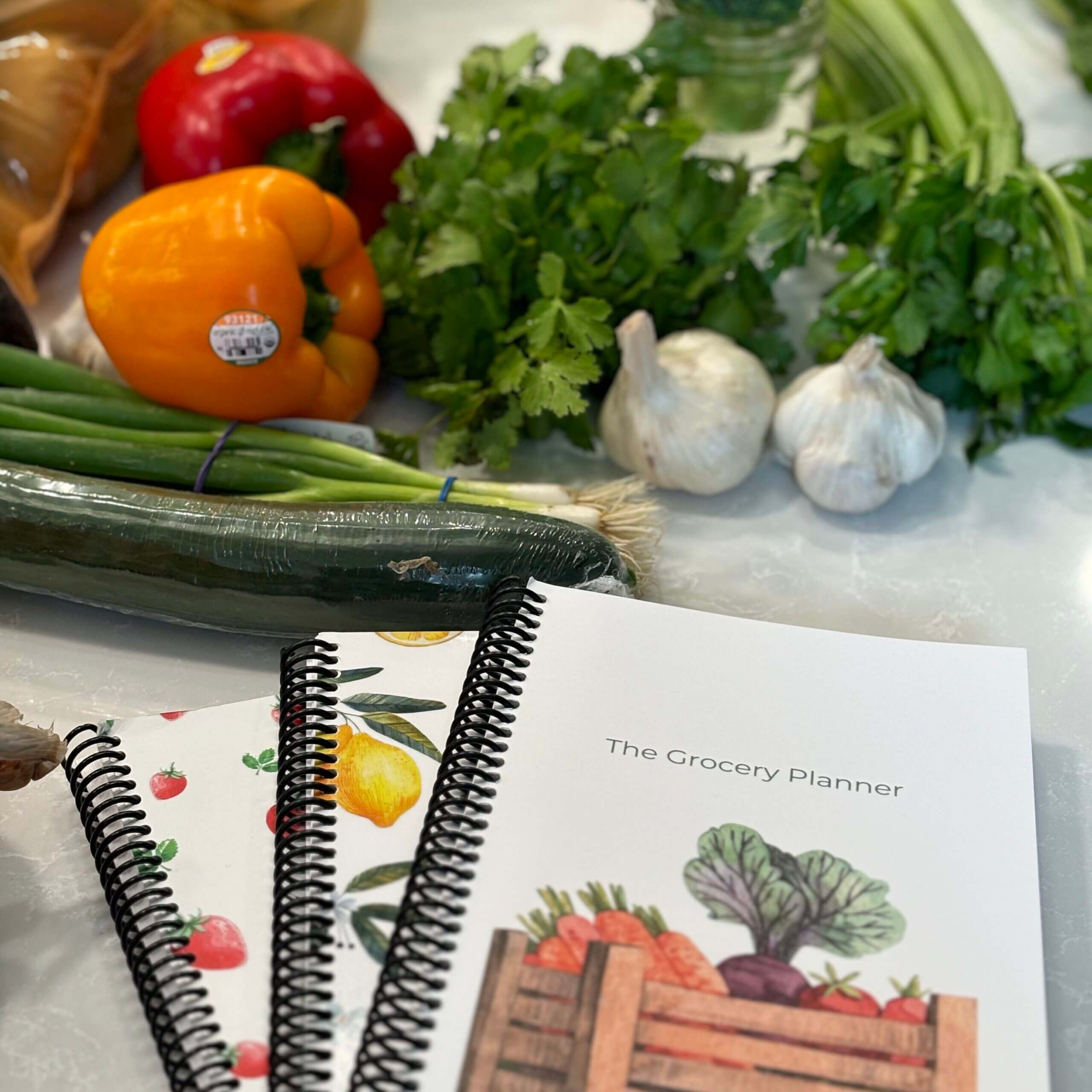 grocery planners laying on the counter with vegetables