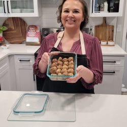 Amy holding a glass container with protein balls in the kitchen